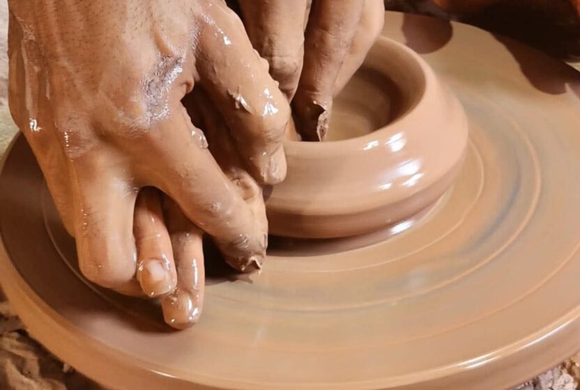 Hands shaping clay on a potter's wheel in Tunis Village, Fayoum