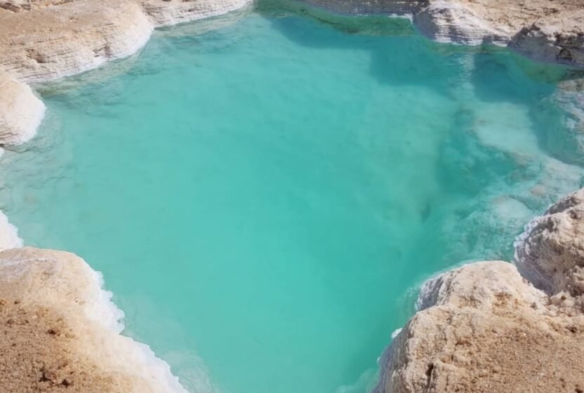 Salt crust around a turquoise lake in Siwa